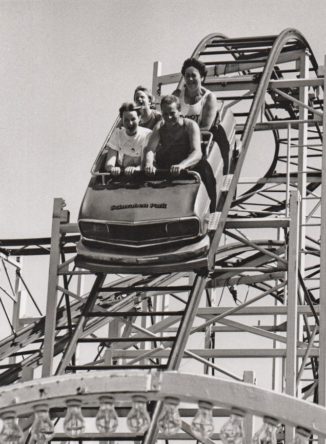Eine Familie in einem Achterbahnwagen mit der Aufschrift "Schwaben Park"