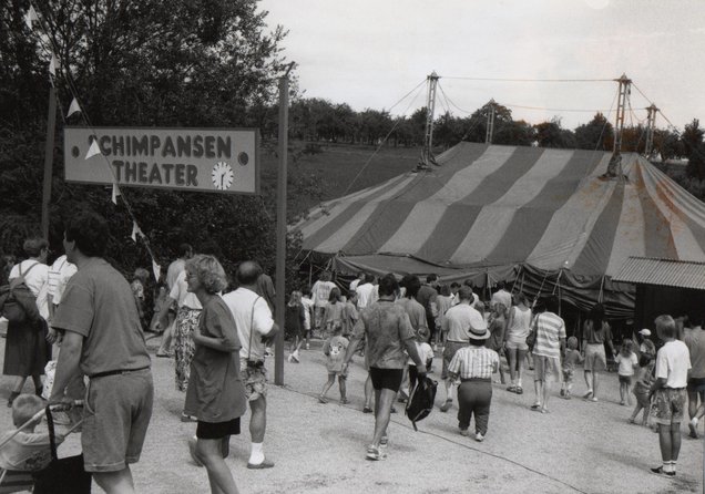 Eine Zuschauermenge vor einem Zelt "Schimpansen Theater"